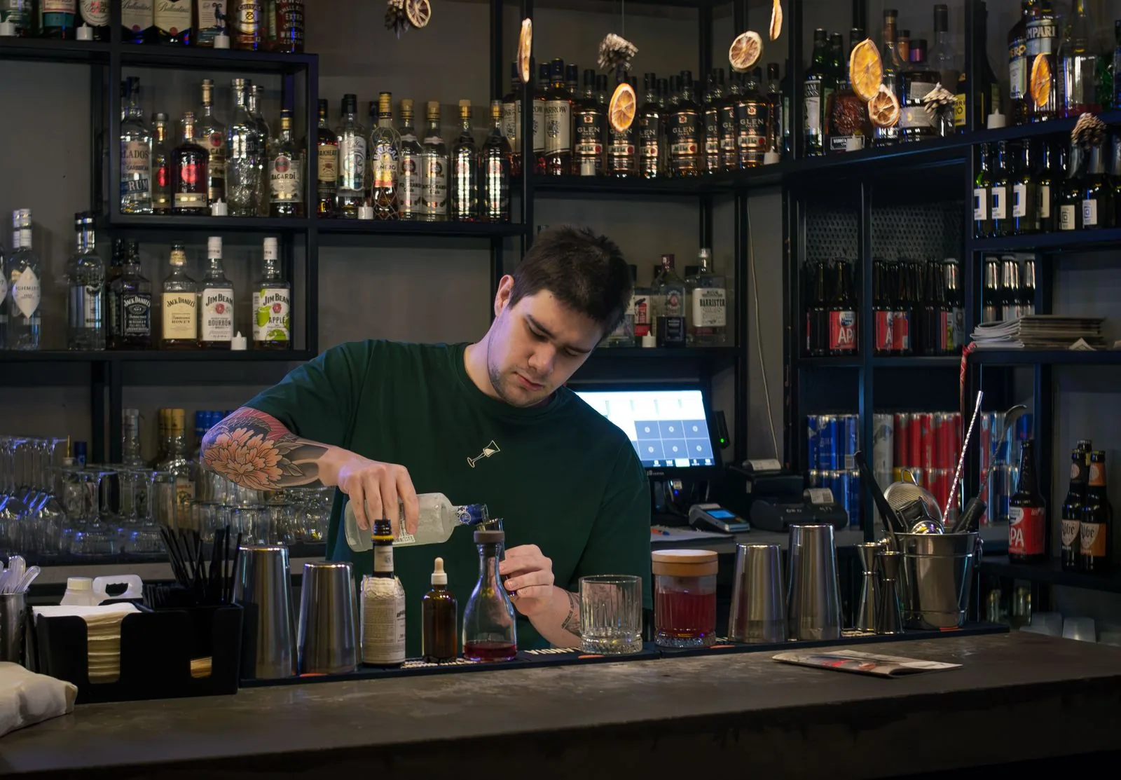 A bartender making a drink behind the bar of a small independent bar