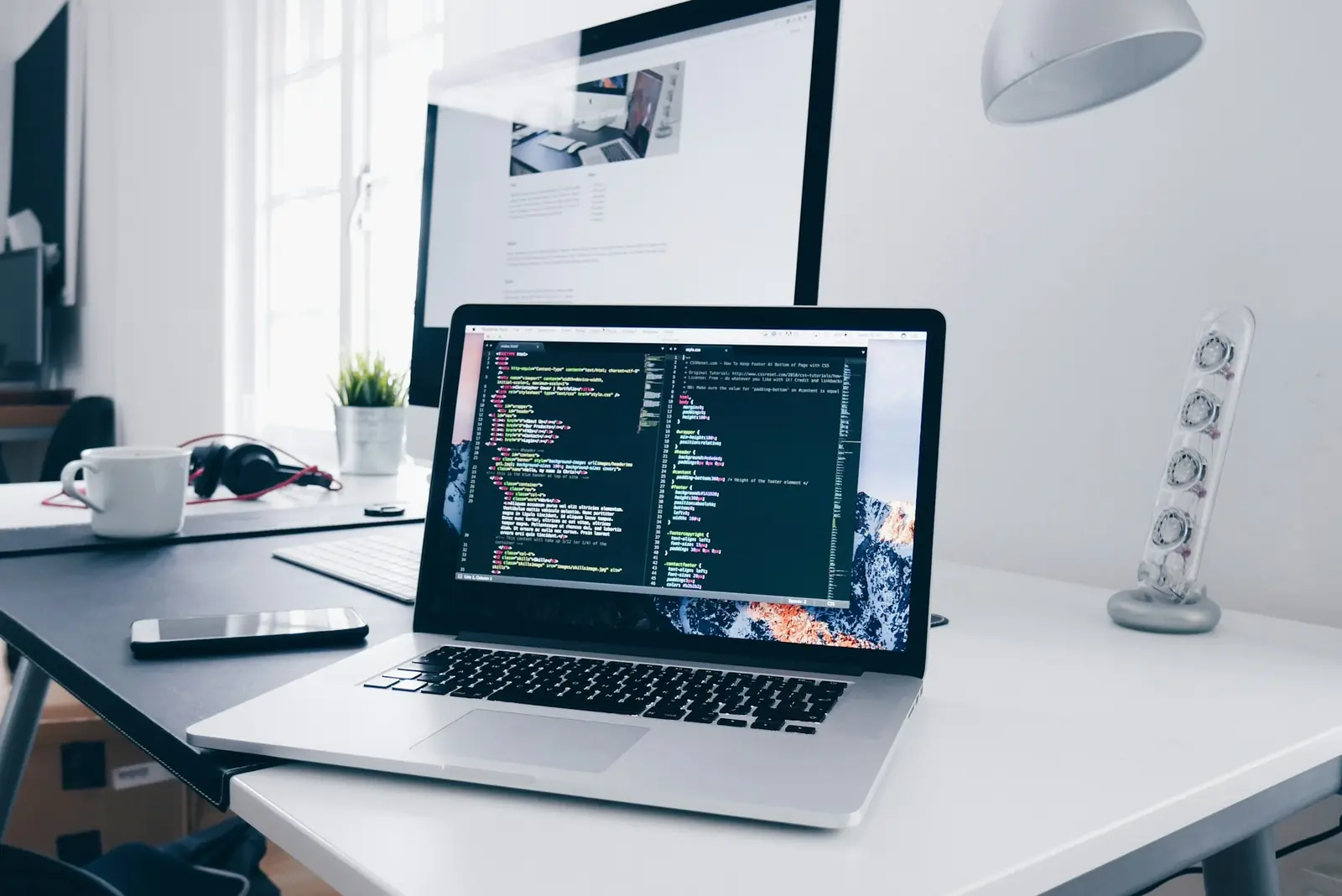 A laptop with code on its screen on a busy desk