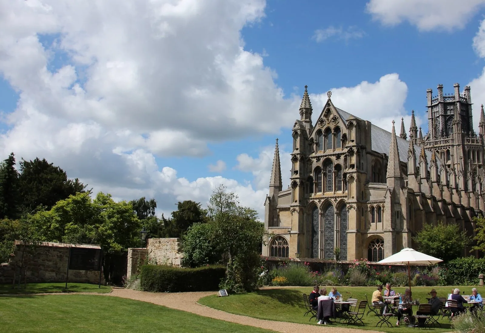 Ely Cathedral seen across the park, with people sitting outside