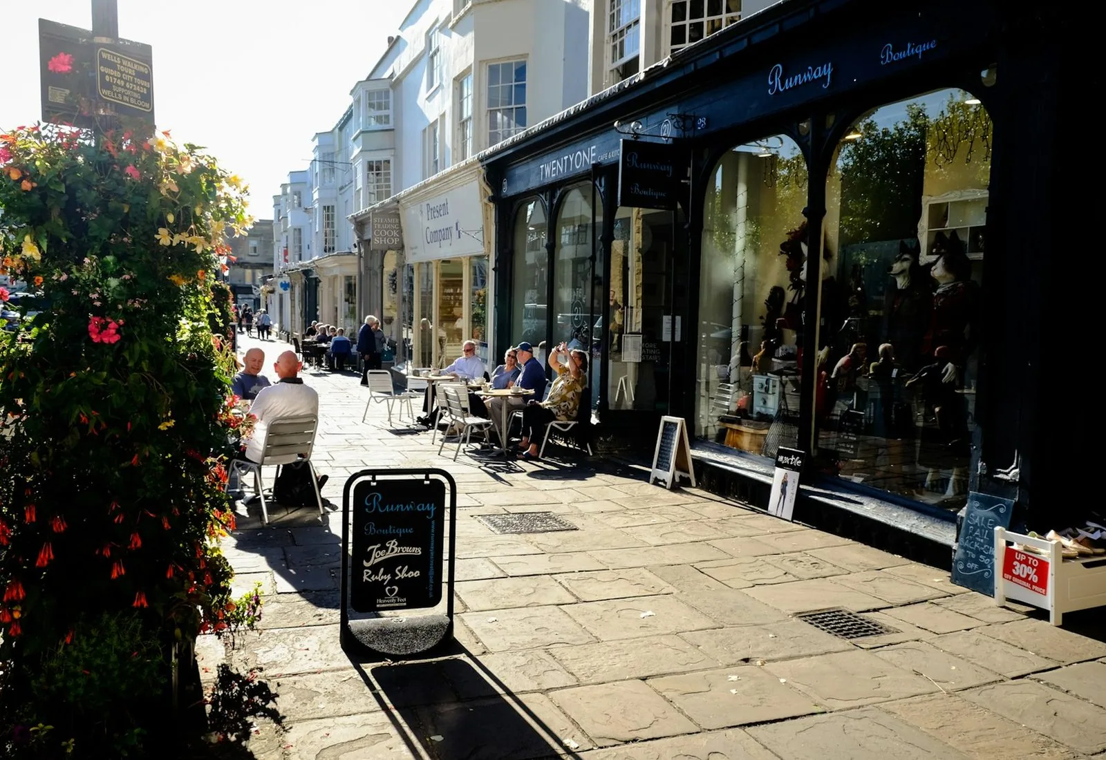 A high street of independent shops, with people at pavement tables