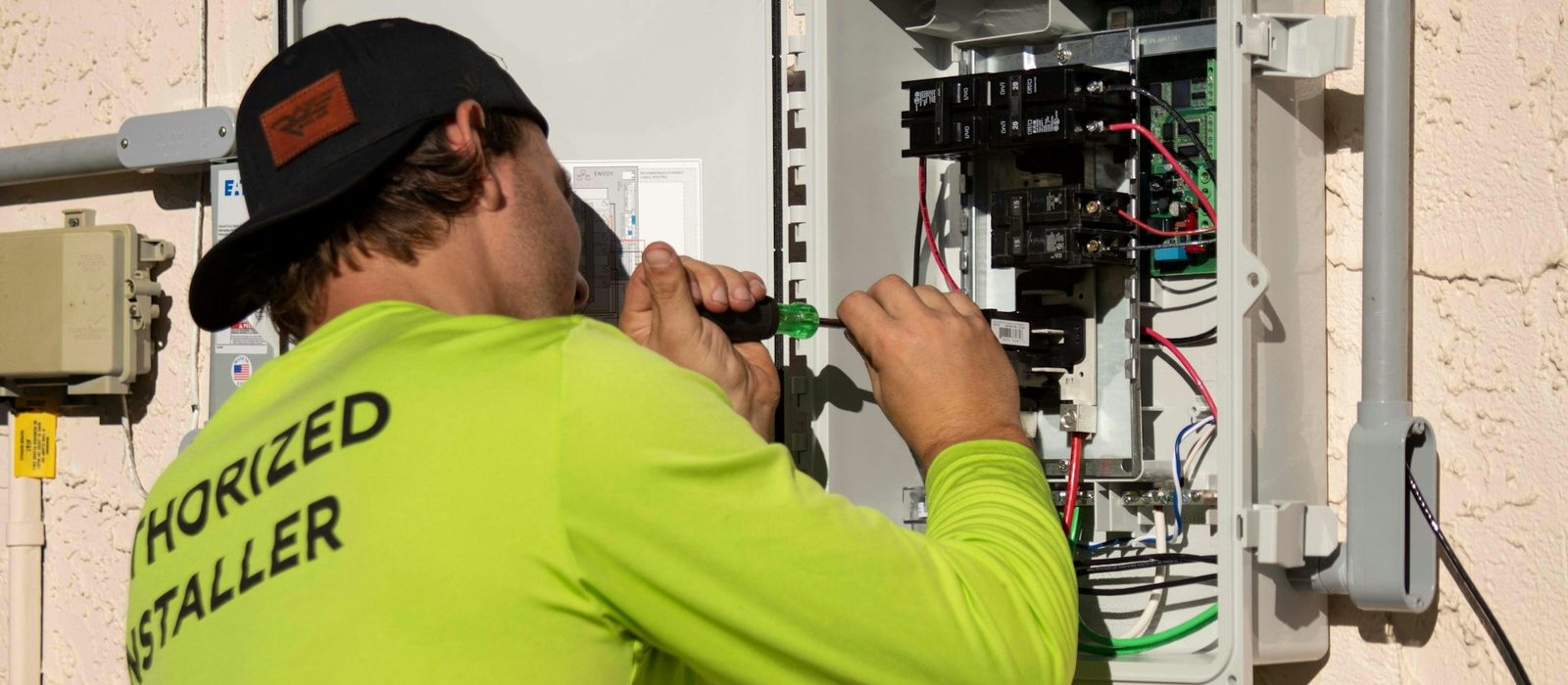 A tradesman in hi vis working with a screwdriver